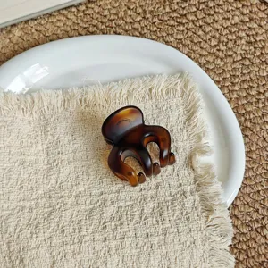 Small brown tortoiseshell hair claw clip detail view, elegant minimalist hair accessory for women.