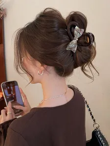 Detail shot of a large hair claw featuring an iridescent bow, perfect for stylish updos.