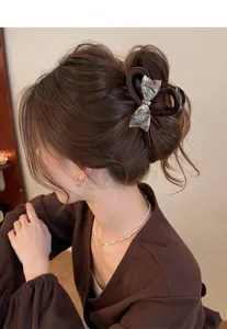 Elegant hair claw featuring an iridescent bow design, perfect for styling upscale buns.