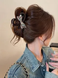 Detail shot of the elegant iridescent bow hair claw clip worn on hair for chic hairstyles.