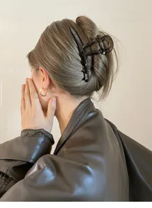 Detail shot of a stylish dark geometric hair claw clip worn on styled hair, autumn accessory.