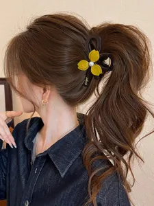 Detail shot of elegant floral hair claw with yellow petals and pearl center, stylish ponytail clip.