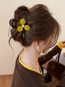 Detail shot of flower pearl hair claw clip, elegant yellow floral design with a pearl center.