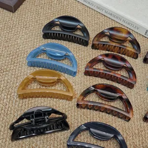 Detailed close-up of large semi-circular hair claws in various stylish colors and tortoise shell.