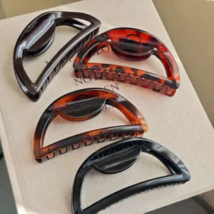 Detail view of large semi-circular hair claws featuring tortoiseshell and black finishes.