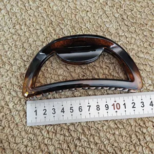 Close-up detail of a tortoiseshell half-circle hair claw clip showing size scale.