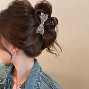 Iridescent bow hair claw clip for women, elegant large shark clip for thick hair styling.