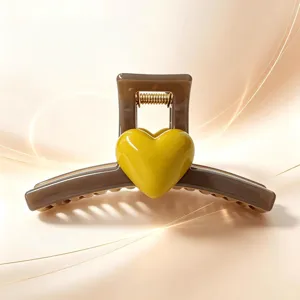 Detailed view of large brown hair claw clip featuring a glossy yellow 3D heart ornament.