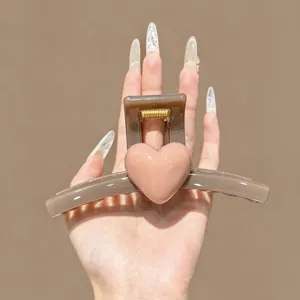 Close up of brown hair claw clip featuring a cute pink 3D heart design and gold spring.
