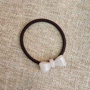 Primo piano dettagliato del grazioso elastico per capelli con fiocco in acetato resistente.