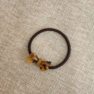 Dettaglio elastico capelli con fiocco in acetato, corda marrone, accessorio per capelli carino.