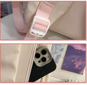 Vue détail du sac à dos montrant la boucle de sangle rose et la petite poche latérale.