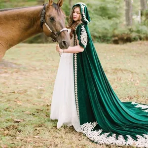 Detailed view of the dark green velvet hooded cloak featuring intricate gold embroidery and lace trim.