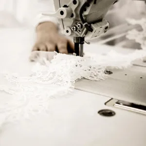 Detailed shot of delicate white lace sewing craftsmanship, highlighting exquisite garment texture.