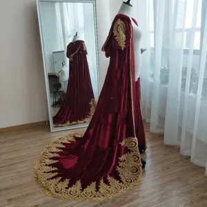 Detailed view of dark red velvet hooded cloak with intricate gold embroidery and long train.