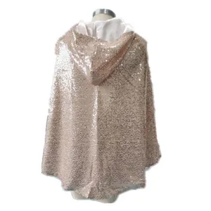 Close-up detail of the glittering sequin hooded cape, showing sparkling rose gold texture.