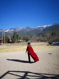 Outdoor scene detail shot featuring a long red velvet hooded cape for stage performances.
