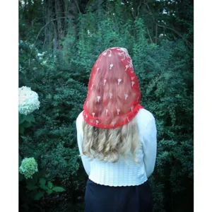 Outdoor detail view showing a red mesh embroidered chapel veil with delicate floral patterns.