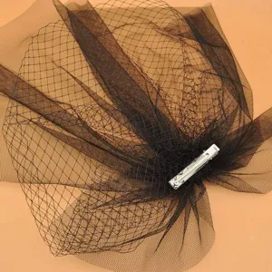 Close-up detail of black mesh birdcage veil with metal clip, elegant bridal hair accessory.
