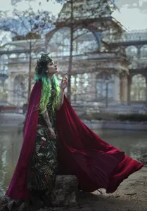 Detailed view of the elegant long red velvet cloak in an outdoor atmospheric scene setting.