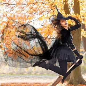 Detailed scene showing the flowing black witch cape and tutu costume in an autumn outdoor setting.