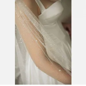 Detailed close-up of bridal glitter mesh capelet, featuring ivory sheer fabric and pearl details.
