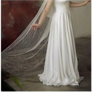 Detailed view of long white bridal veil cape with pearls and glitter sparkling mesh.
