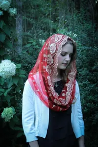 Detailed close-up view of red mesh embroidered head covering, featuring elegant floral lace pattern.