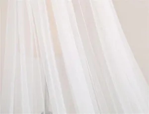 Wit bruids tule stof detail close-up met zachte textuur en elegante drapeffecten.