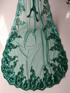 Detailed close-up of green sequin embroidered lace veil fabric showing intricate floral patterns.