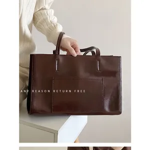 Detail shot of a large capacity dark brown leather tote bag with dual handles and front pocket.
