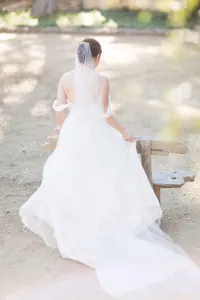 Detailed view of a long bridal veil with a secure comb and cut edge in a natural outdoor scene.