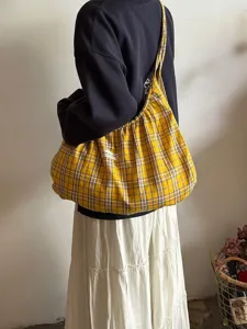 Detail view of the yellow plaid slouchy tote bag, showing soft pleated fabric and strap design.