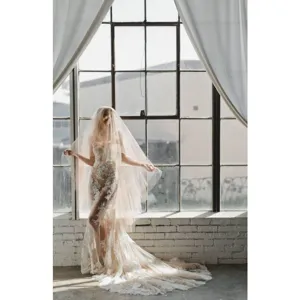Detail shot of elegant bridal wedding veil and lace gown in a vintage loft window setting.