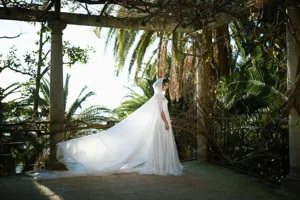 Details of the elegant white hooded chiffon cloak showcasing long flowing train and scenic outdoor backdrop.