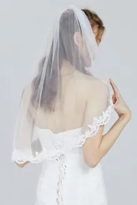 Detailed view of white bridal veil featuring delicate lace trim and mesh fabric with comb.