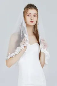 Elegant bridal veil with delicate lace embroidery, mesh fabric, and comb for wedding details.