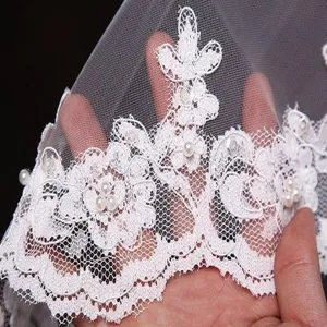 Dettaglio velo da sposa in rete di perle ricamato in pizzo bianco per accessori.