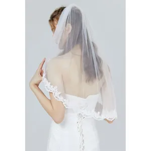 Elegant white bridal veil with delicate lace embroidery and comb, perfect for wedding day.