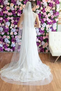 Detailed view of long cathedral wedding veil with delicate pearls and floral background scene.