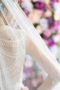 Detailed close-up of bridal pearl mesh veil and lace gown, elegant wedding photography.