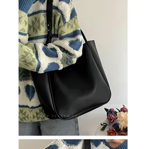 Λεπτομερής λύψη της κομψής μαύρης τσάντας shopper που παρουσιάζεται σε καθημερινό σύνολο.