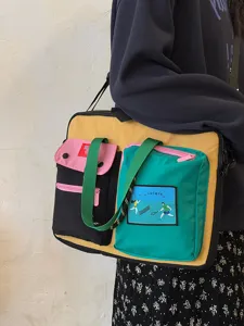 Close-up detail of the color-blocked canvas laptop shoulder bag with multi pockets.