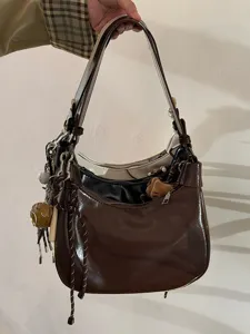 Detailansicht der stylischen braunen Lackleder-Hobo-Umhängetasche mit süßen Anhängern.
