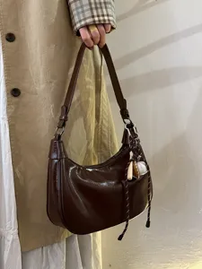 Detailaufnahme der eleganten dunkelbraunen Lackleder-Hobotasche mit sportlichem Anhänger.