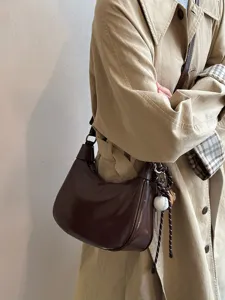 Detailansicht der retro braunen Achseltasche in Beutelform mit Baseballanhänger am Modell.