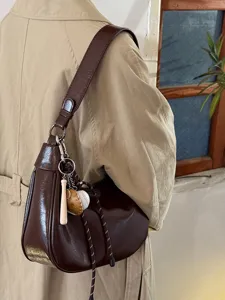 Braune Vintage Schultertasche Detailaufnahme mit hochwertiger Lederoptik und Anhänger.