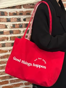 Rote Canvas Tragetasche Detailansicht mit weißem Buchstabenprint und bequemem Schulterriemen.