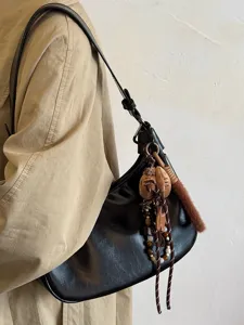 Detailansicht einer stilvollen schwarzen Leder-Hobo-Schultertasche mit elegantem Mantel.