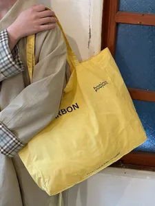 Detail shot of a casual yellow canvas tote bag with printed text, perfect for everyday use.